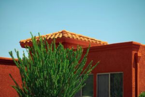 An adobe home in Arizona with a bright green tree against a blue sky.