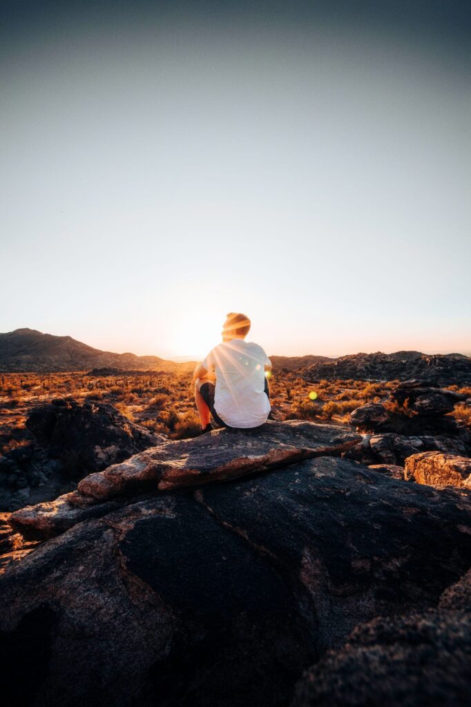 A young person sits on a rock in the Arizona landscape
